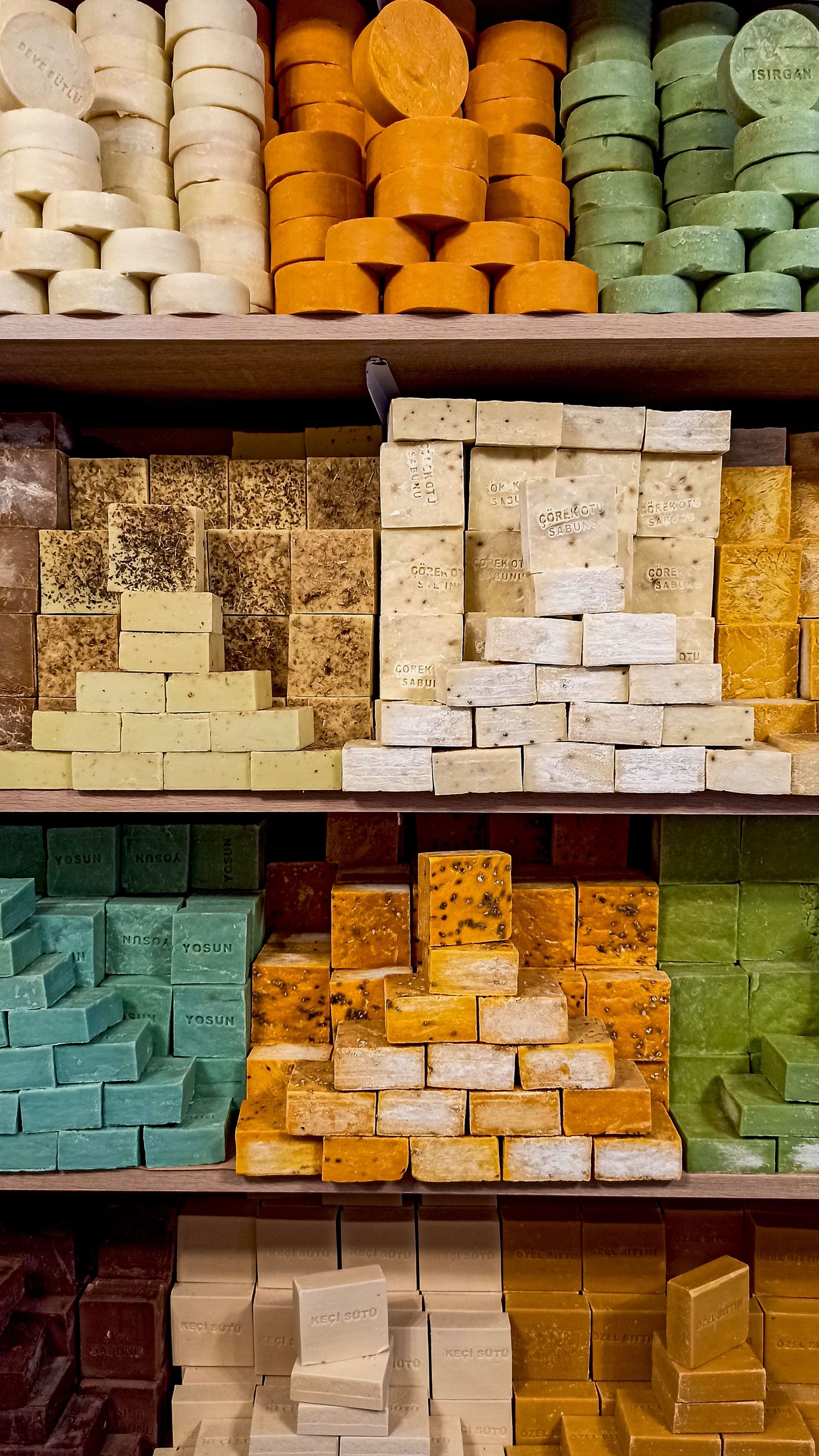 Vibrant assortment of handmade soaps neatly arranged on shelves in a Mardin market shop.